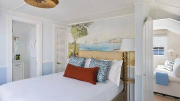 A bedroom with a bed, a nightstand, a lamp, and a painting on the wall.