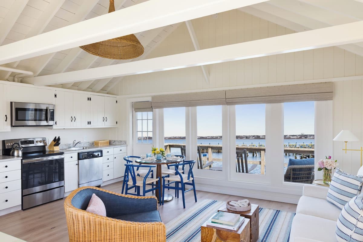 A spacious kitchen with white cabinets, a stainless steel oven, and a large window overlooking a dock.