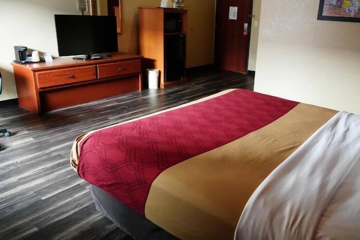 A hotel room with a bed, a desk, a television, and a wardrobe.