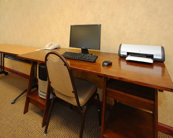 A wooden desk with a desktop computer, a printer, a telephone, and a chair. - Econo Lodge Inn & Suites Kearney South (Kearney)