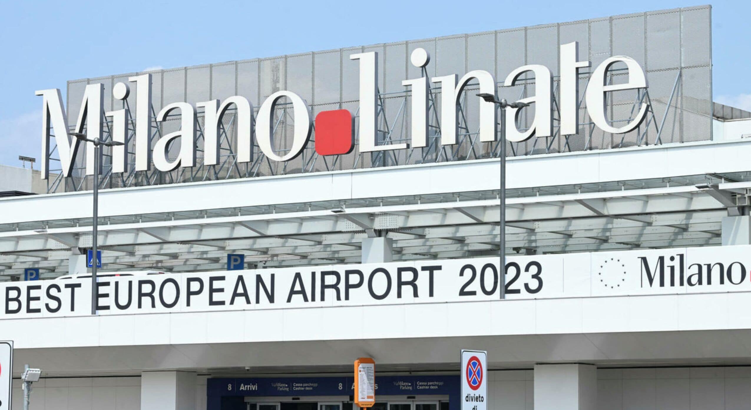 The exterior of Milano-Linate Airport with the text "BEST EUROPEAN AIRPORT 2023" and "Milano" visible.
