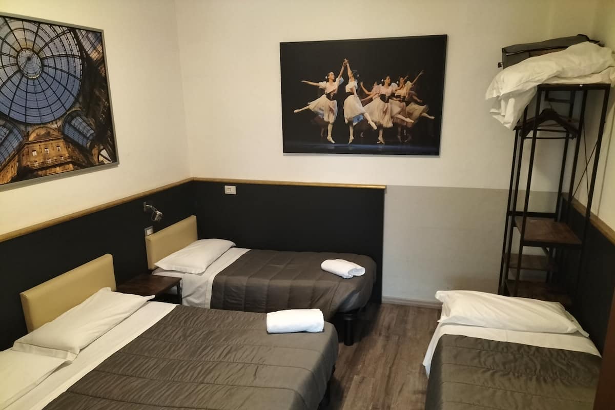 A hotel room with two beds, a painting of dancers, and a bunk bed.