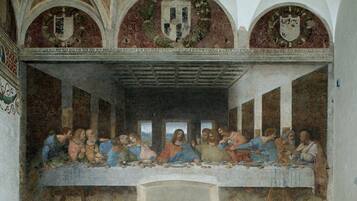 Un affresco dell'Ultima Cena raffigurante un lungo tavolo e figure sedute attorno.