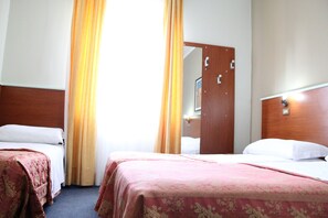 A hotel room with two beds, a wooden headboard, a mirror, and a window with curtains. - Hotel Dateo (Milan)