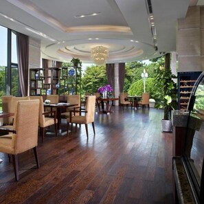 A spacious indoor area with a wooden floor, seating arrangements, and a bookshelf. - Zhejiang Xizi Hotel (Hangzhou)
