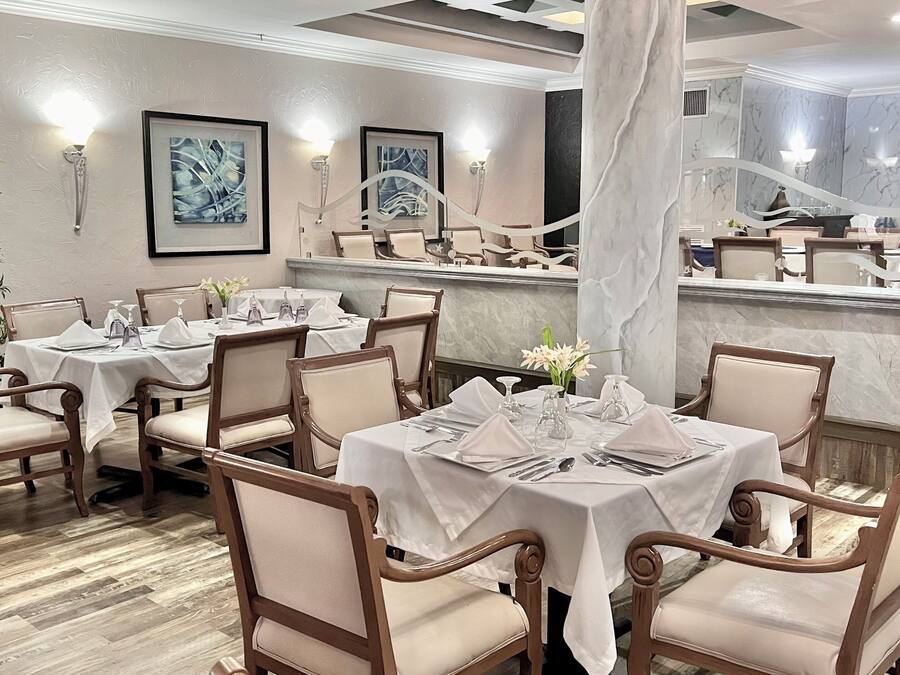 A restaurant with multiple tables, chairs, and framed artwork on the walls.