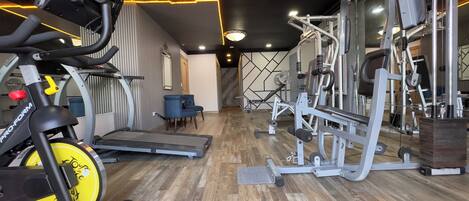 Un gimnasio con equipo de ejercicio, cinta de correr y un espejo.