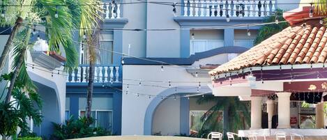 Un hotel con piscina, palmeras y techo de tejas.