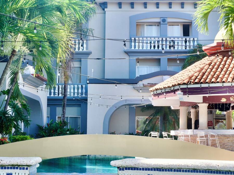 Un hôtel doté d’une piscine, de palmiers et d’un toit recouvert de tuiles.