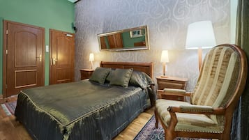 Quarto de hotel com uma cama grande, duas mesas de cabeceira, uma cadeira, um espelho e parede estampada.