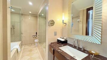 A modern bathroom with a glass-enclosed shower, a marble sink, and a large mirror with a unique frame.