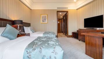 A hotel room with a bed, a desk, a television, and a framed picture on the wall.