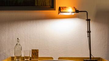 A desk with a lamp, a chair, a bottle, and a glass.
