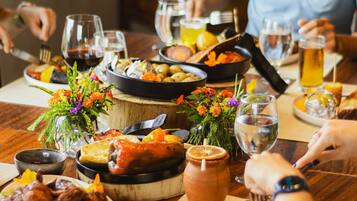A dining table with various dishes, drinks, and a vase of flowers.