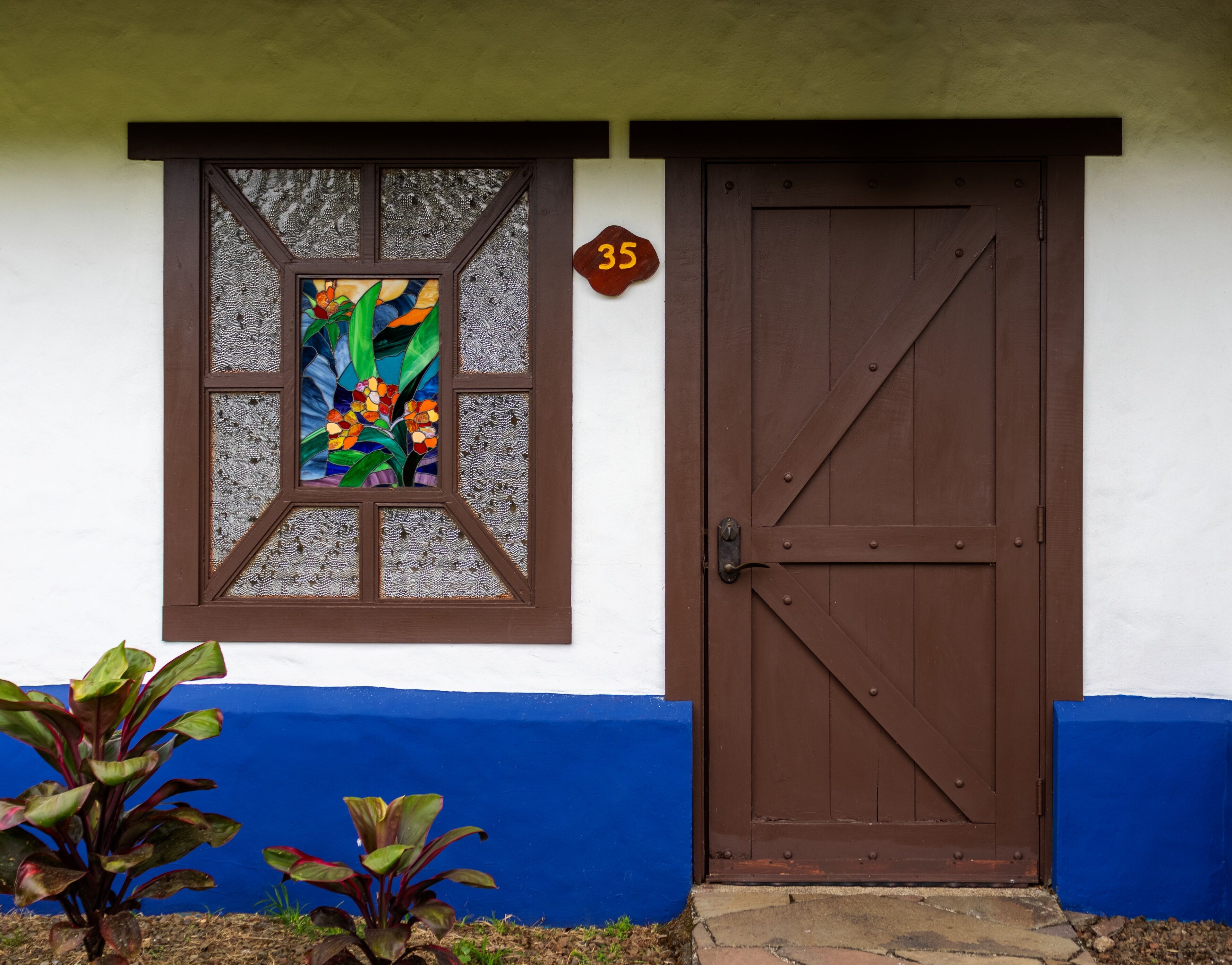 A house with a brown door and a window with a colorful stained glass design.