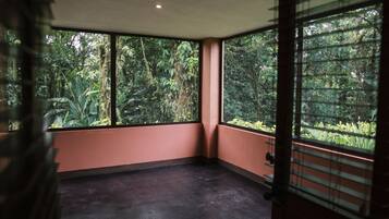A corner room with large windows overlooking dense greenery.