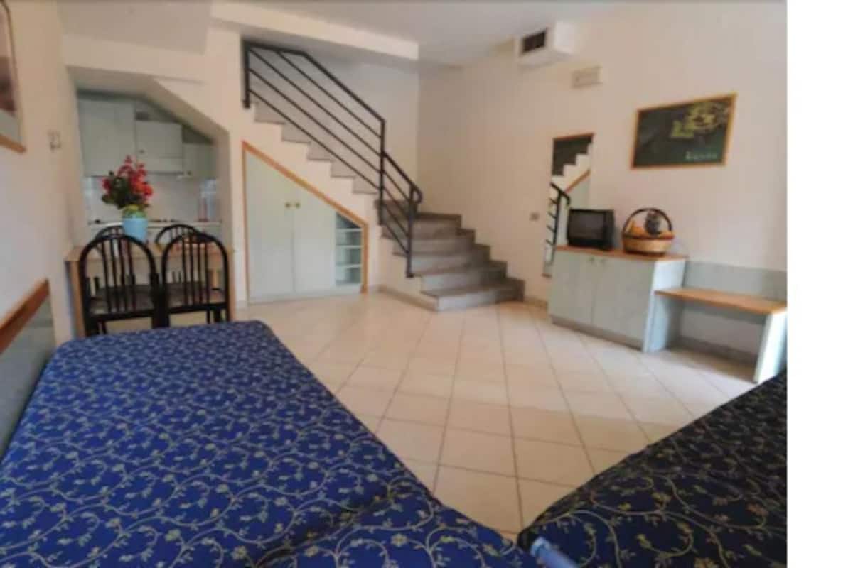 A staircase leading to a landing with a bed and a chair.