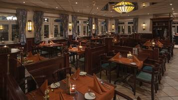 A restaurant with multiple dining tables, each set with plates, cutlery, and glasses.