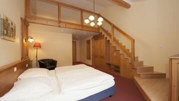 Une chambre avec un grand lit, un escalier en bois et une vue sur le couloir.