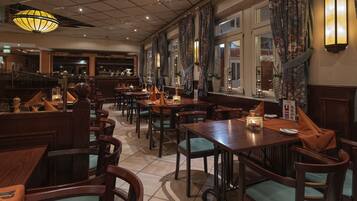 A restaurant with wooden tables and chairs, a bar area, and decorative lighting.