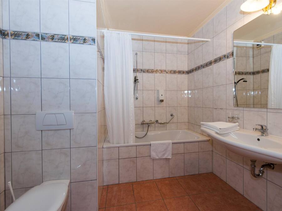 A bathroom with a bathtub, a toilet, a sink, and a mirror.
