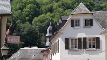 A hotel with a sign, a building with a steep roof, and a castle in the background.