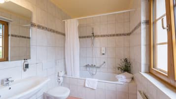 Et badeværelse med vask, toilet, badekar og bruser.