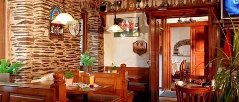 Interior de un restaurante con paredes de piedra, muebles de madera y una variedad de trofeos exhibidos.