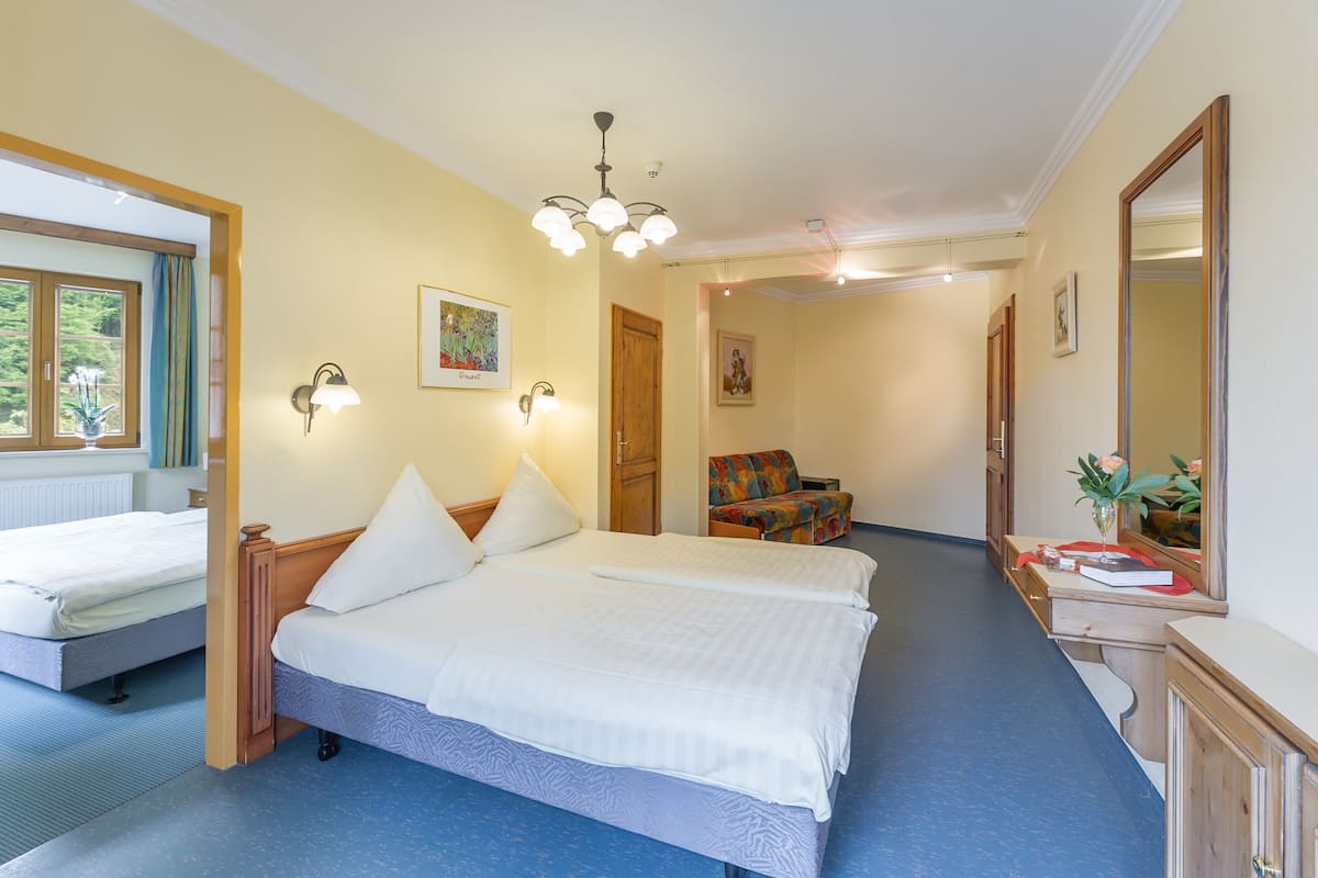 Une chambre d’hôtel avec deux lits, un bureau avec un miroir et une chaise.