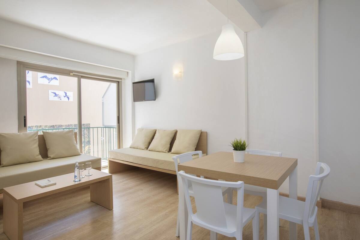 Ein modernes Wohnzimmer mit einer Couch, einem Holztisch und weißen Stühlen.