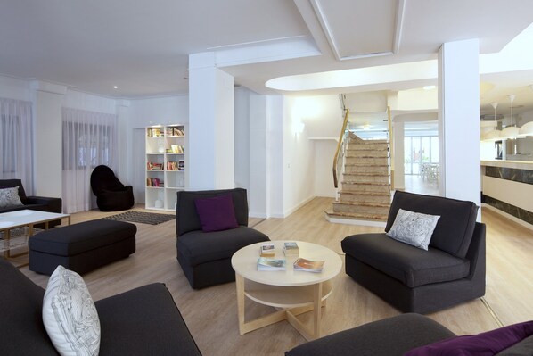 A modern living room with dark sofas, a round coffee table, and a staircase leading to an upper floor.