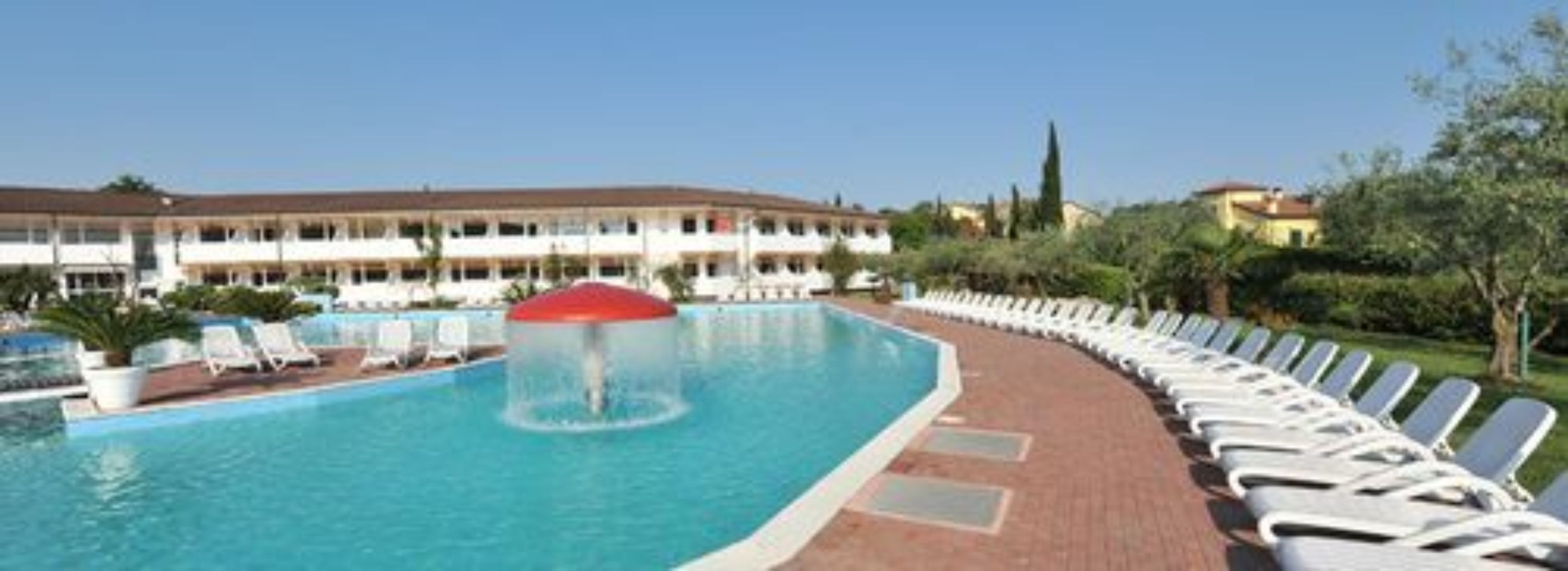 A swimming pool with lounge chairs and a building in the background.