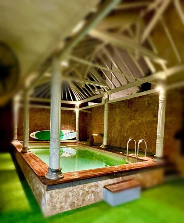Un modelo de piscina con plataforma de madera y pared de piedra.