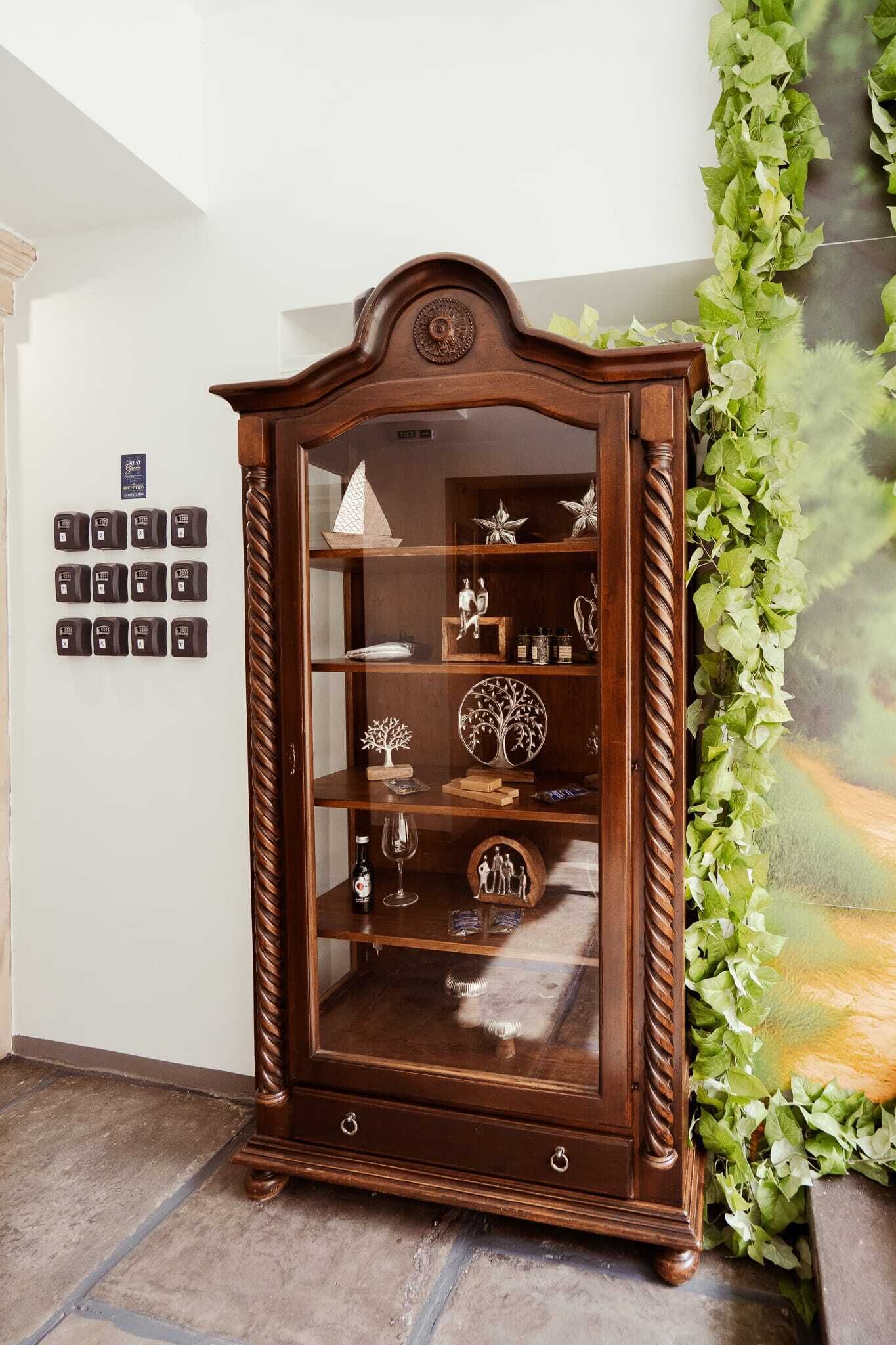 A wooden cabinet with glass doors, a decorative top, and a spiral design on the sides.
