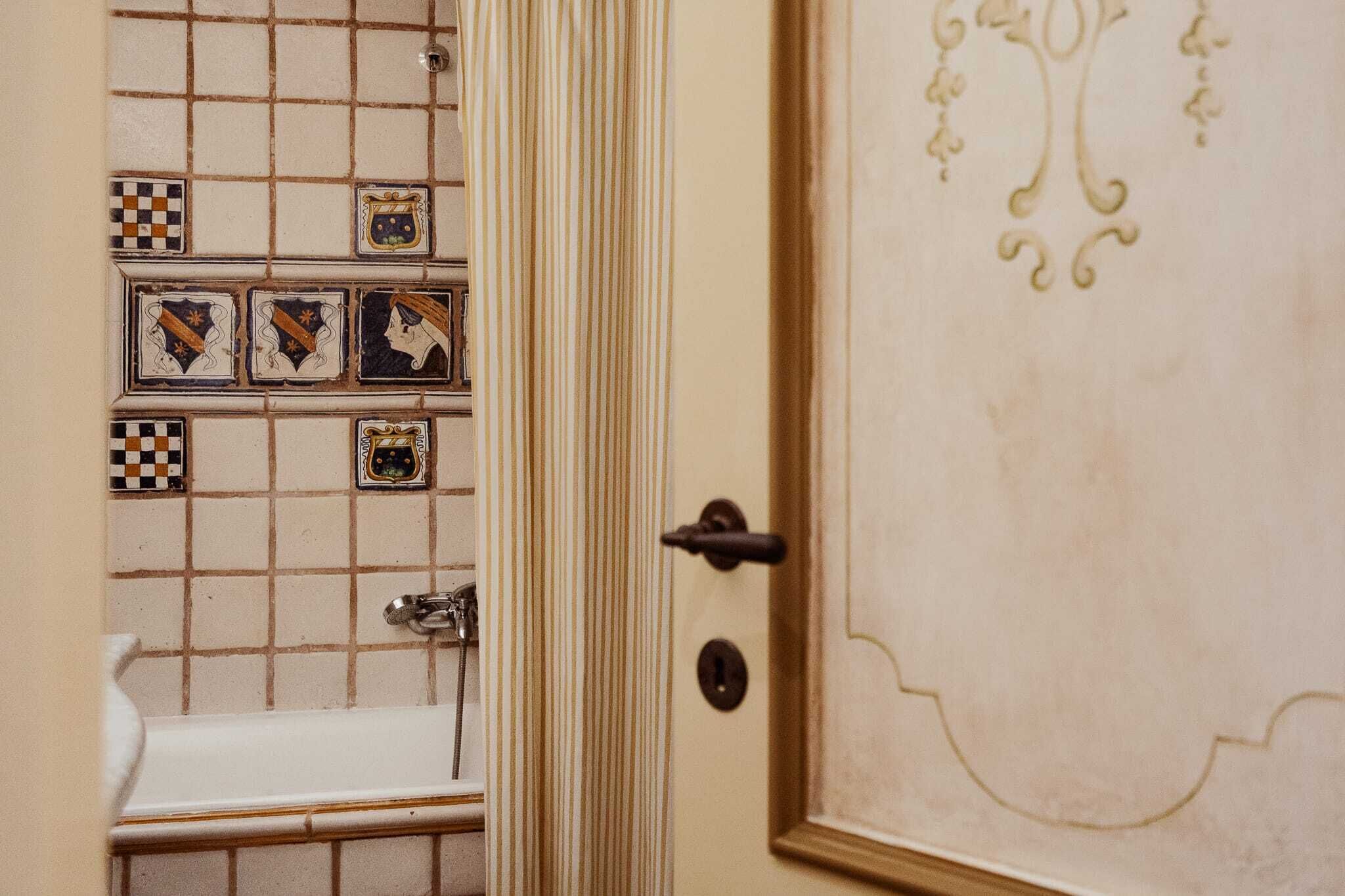 A bathroom with a tiled wall, a sink, and a door with a decorative design.
