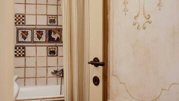 A bathroom with a tiled wall, a sink, and a door with a decorative design.