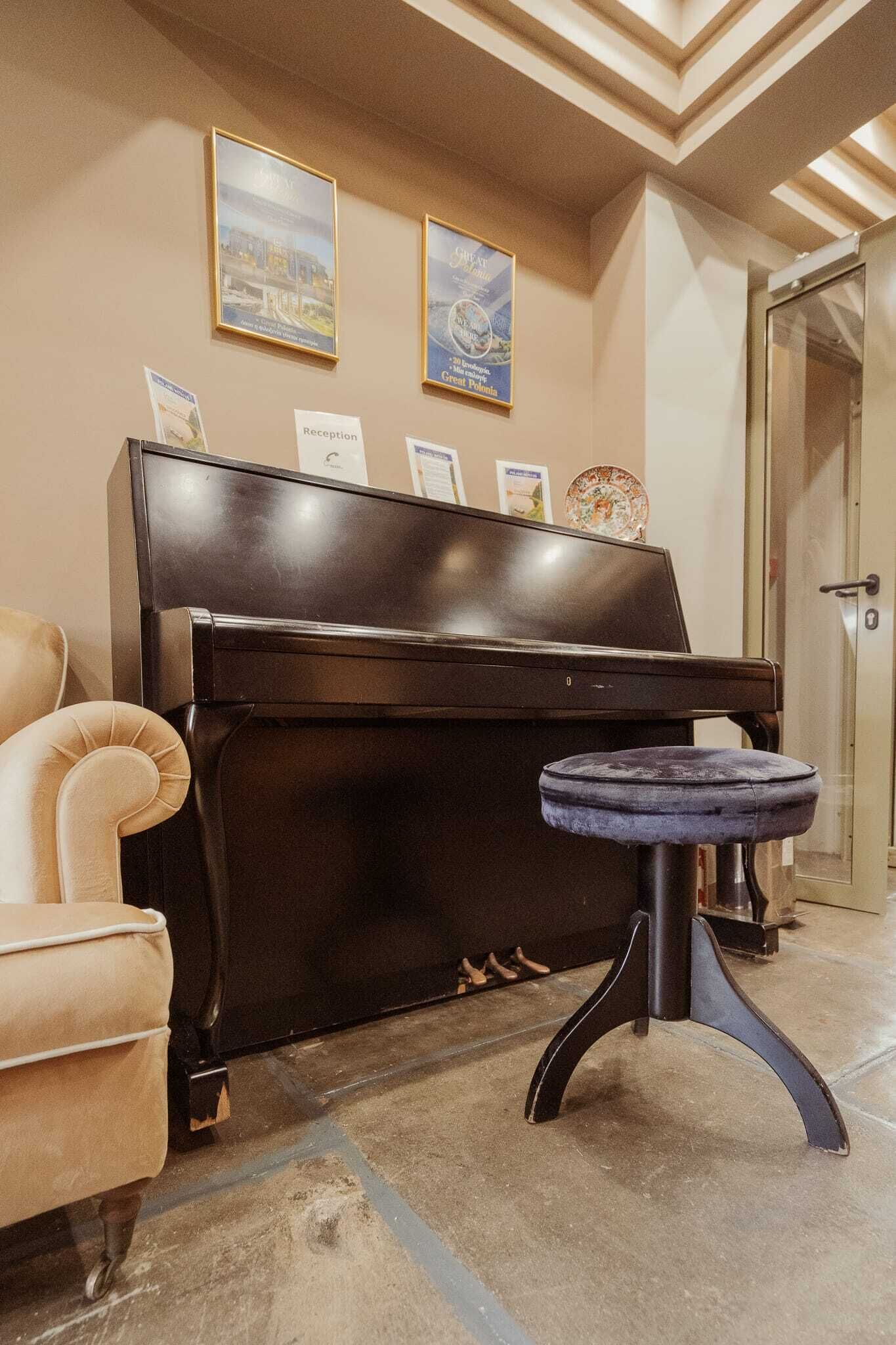 A piano with a stool, a reception sign, and framed pictures on the wall.