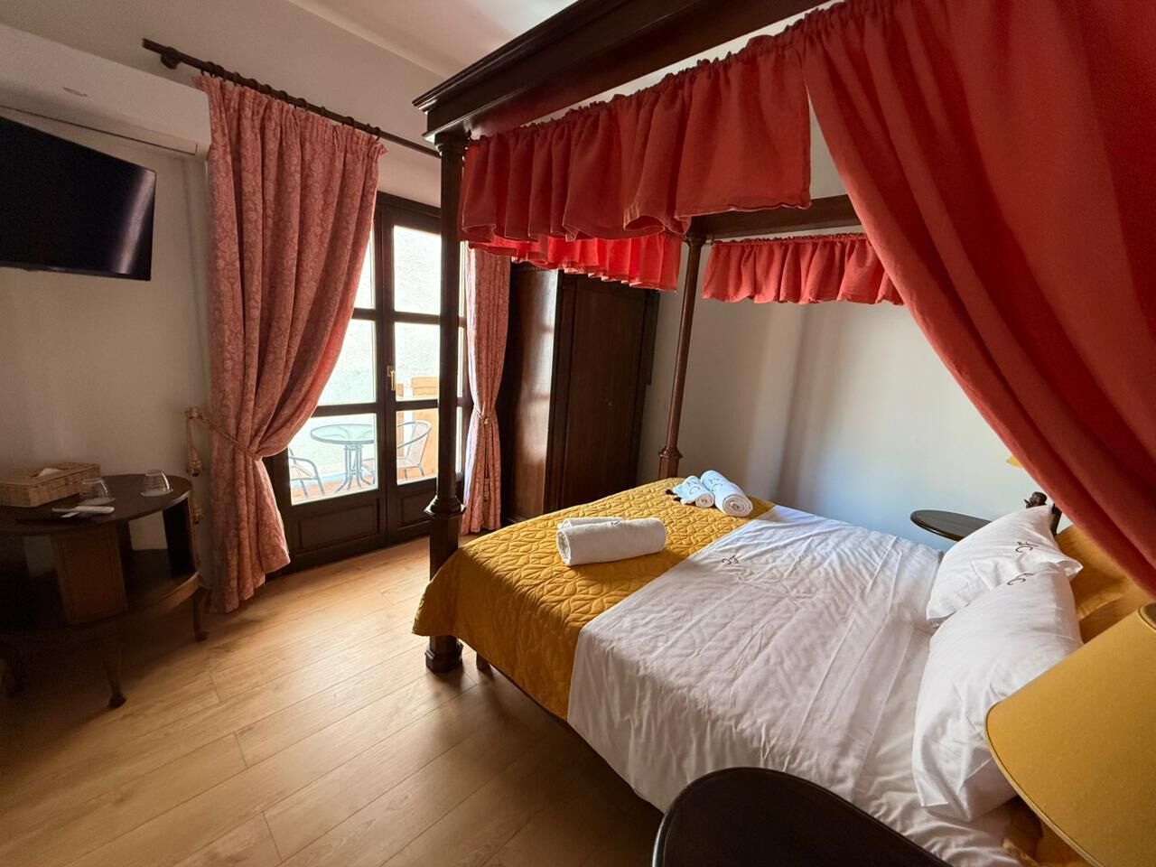 A hotel room with a bed, a desk, and a window with curtains.