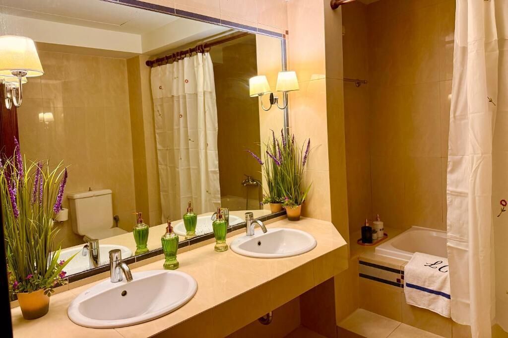 A bathroom with two sinks, a mirror, and a shower.