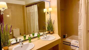 A bathroom with two sinks, a mirror, and a shower.