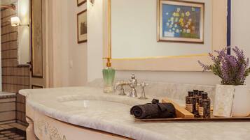 A bathroom with a marble sink, a green soap dispenser, a lavender plant, and a towel.