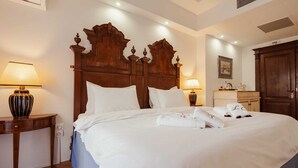 A hotel room with a large bed, two bedside lamps, a wooden headboard, a nightstand, and a wardrobe. - Great Greece Le Convivial Suites & Spa (Xylokastro-Evrostina)