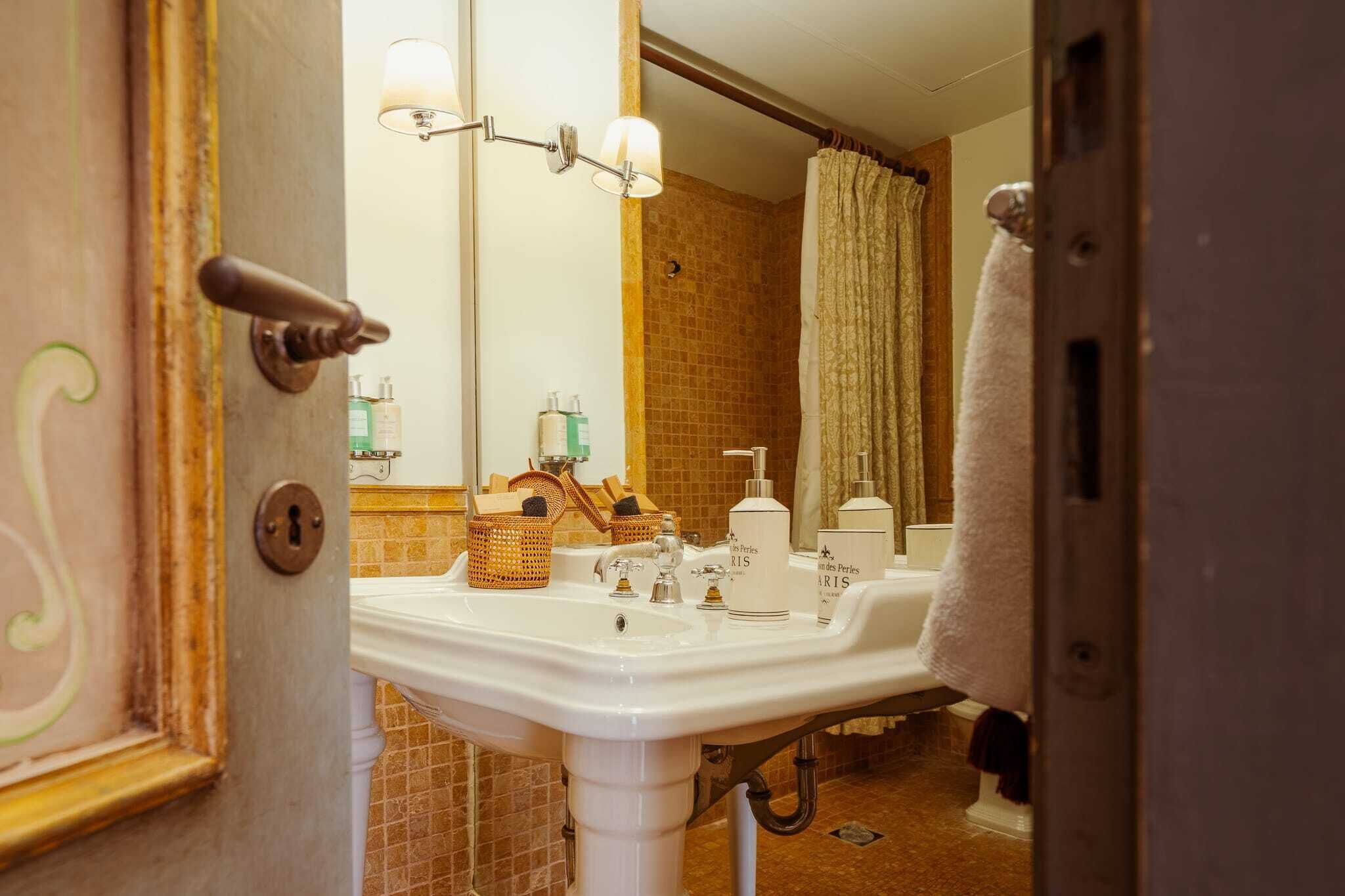 Un baño con lavamanos, espejo, toallero y cortina de ducha.