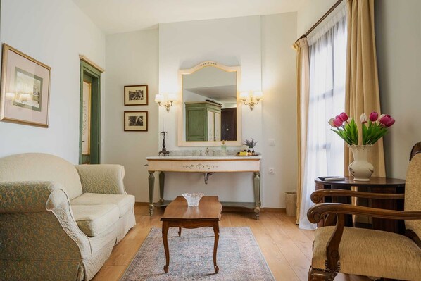 Una sala de estar con un sofá, una mesa de madera, un espejo, una tocador con espejo y un jarrón con flores.