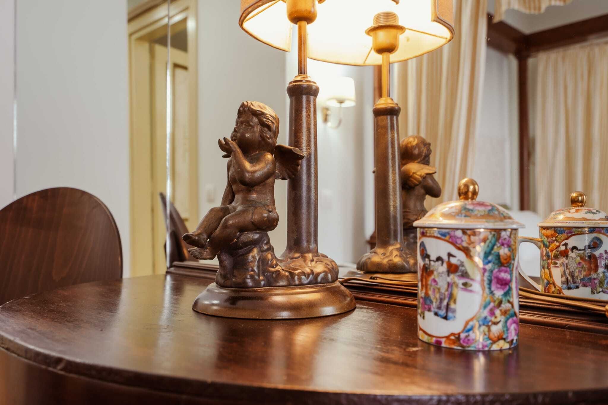 Et træbord med en dekorativ lampe, en statue og detaljerede keramikgenstande.
