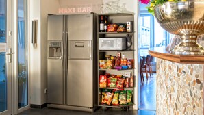 Una cocina con un refrigerador de acero inoxidable, un microondas y estantes llenos de refrigerios.