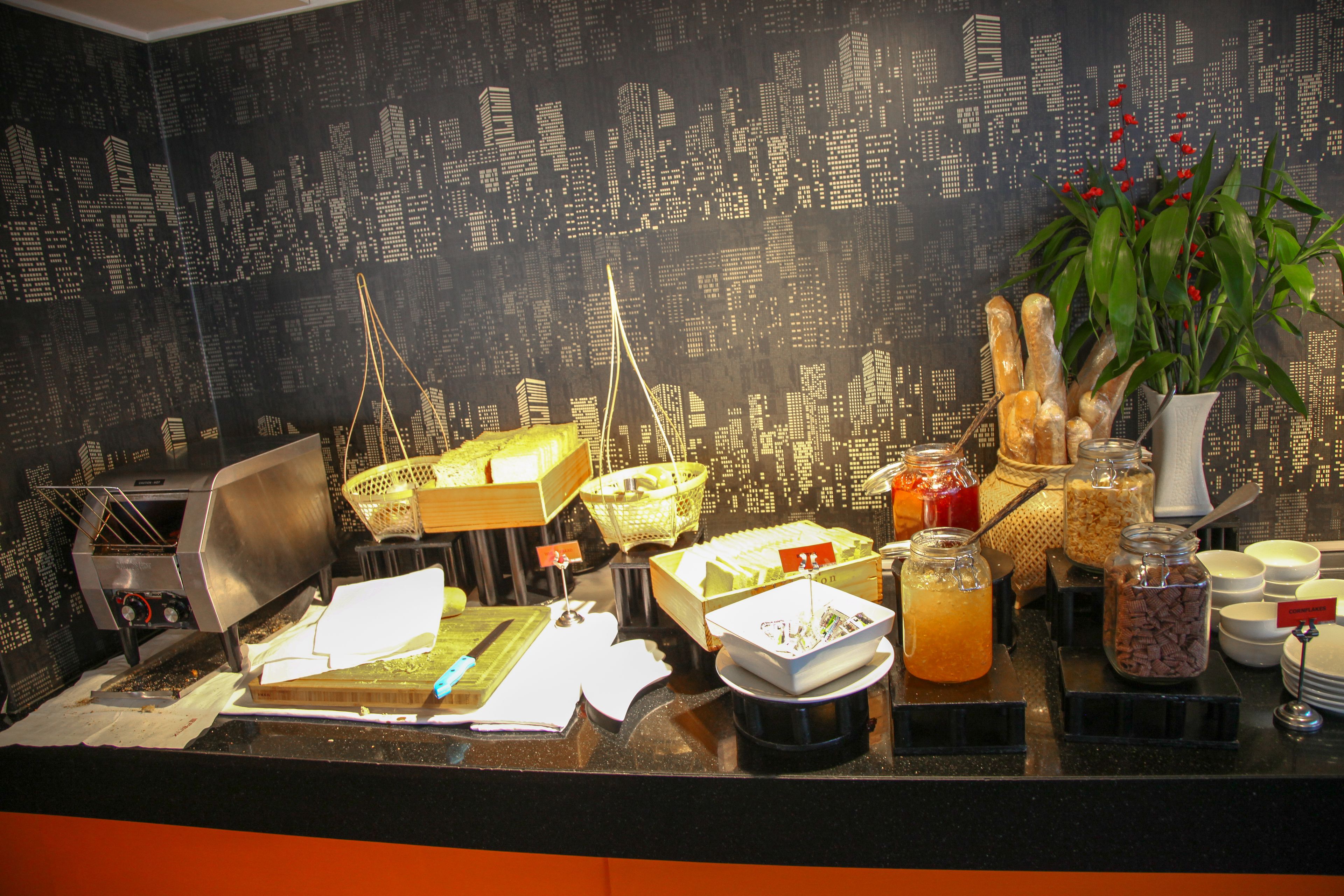 A buffet counter with various food items and a cityscape wallpaper in the background.