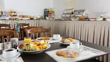 A breakfast buffet with various fruits, pastries, and beverages.