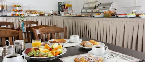 A breakfast buffet with various fruits, pastries, and beverages.