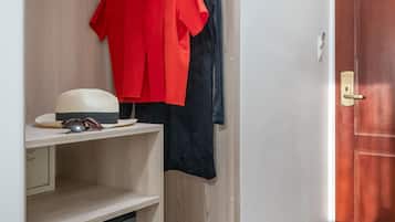 Un vestidor con estantes de madera, una barra para colgar ropa y un armario pequeño.